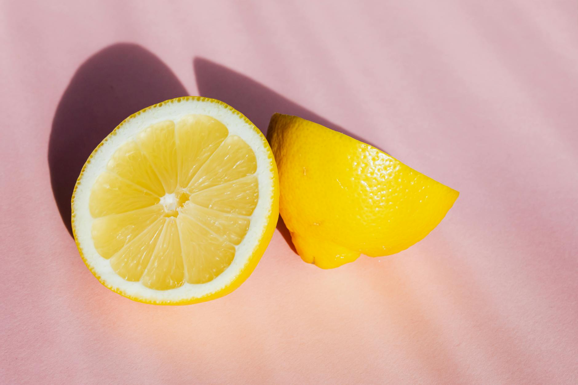 Fresh lemon halves on a pink background in sunlight, symbolizing refreshing renewal