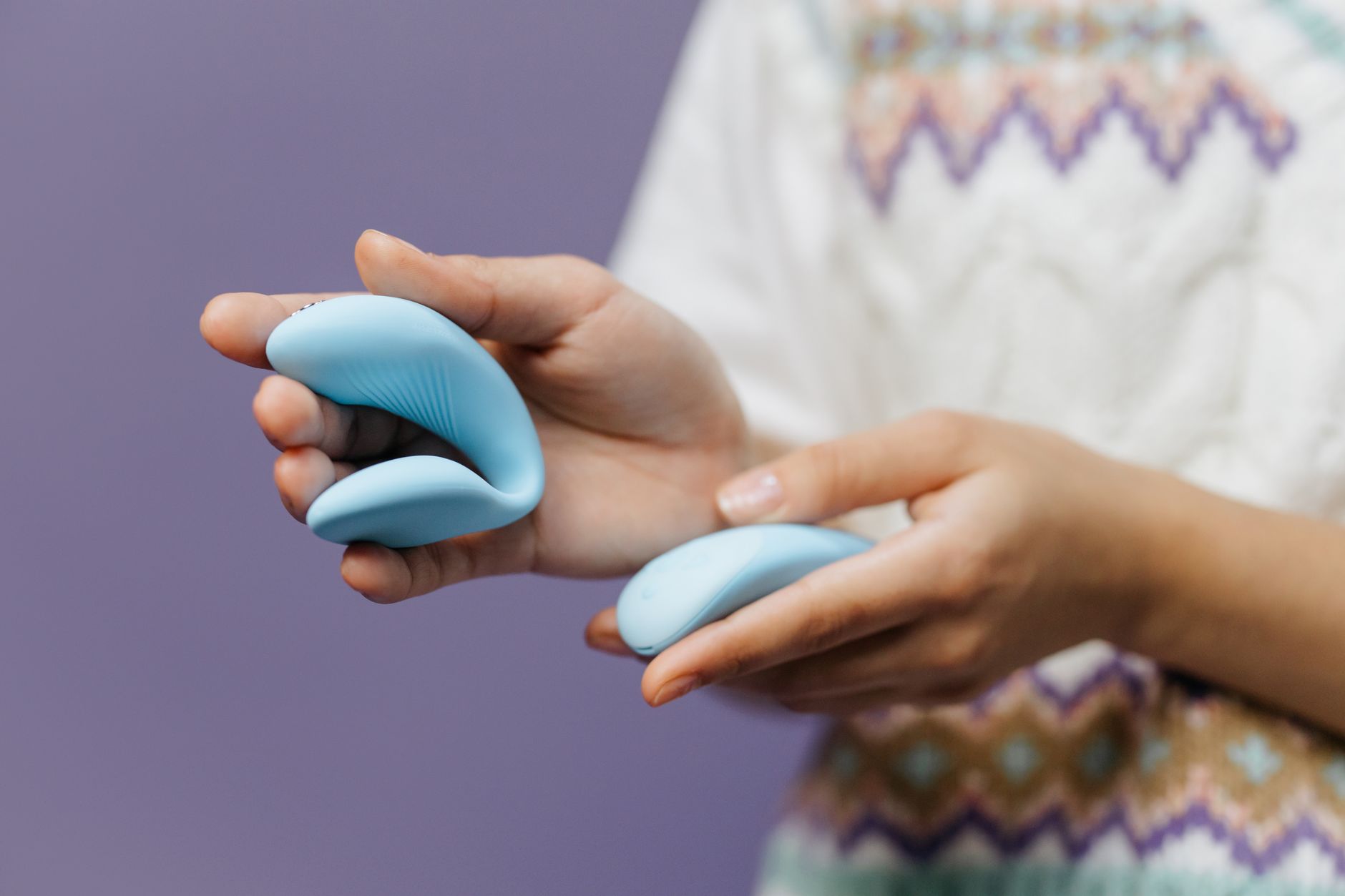 Close-up of hands holding a sleek lemon vibrator against a purple background, symbolizing desire and intimacy